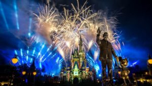 fireworks behind disney world castle with walt disney and mickey mouse statue in front